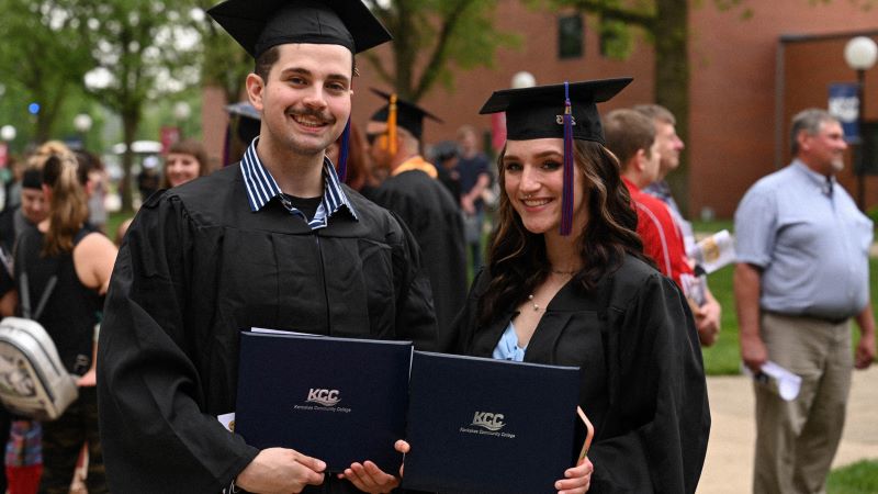 Two students in black cap and gowns after commencement ceremony.