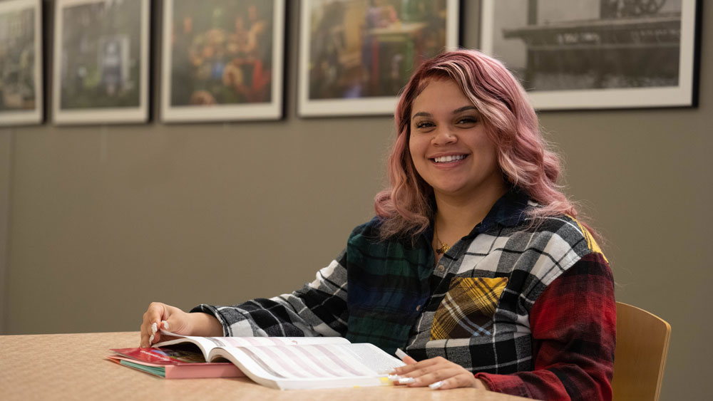 student at a table reading a textbook